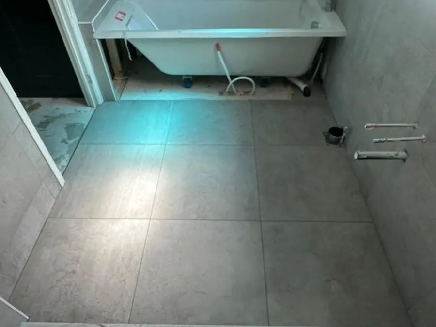 Large-format grey floor tiles around a freestanding bath, Calder Grange show home