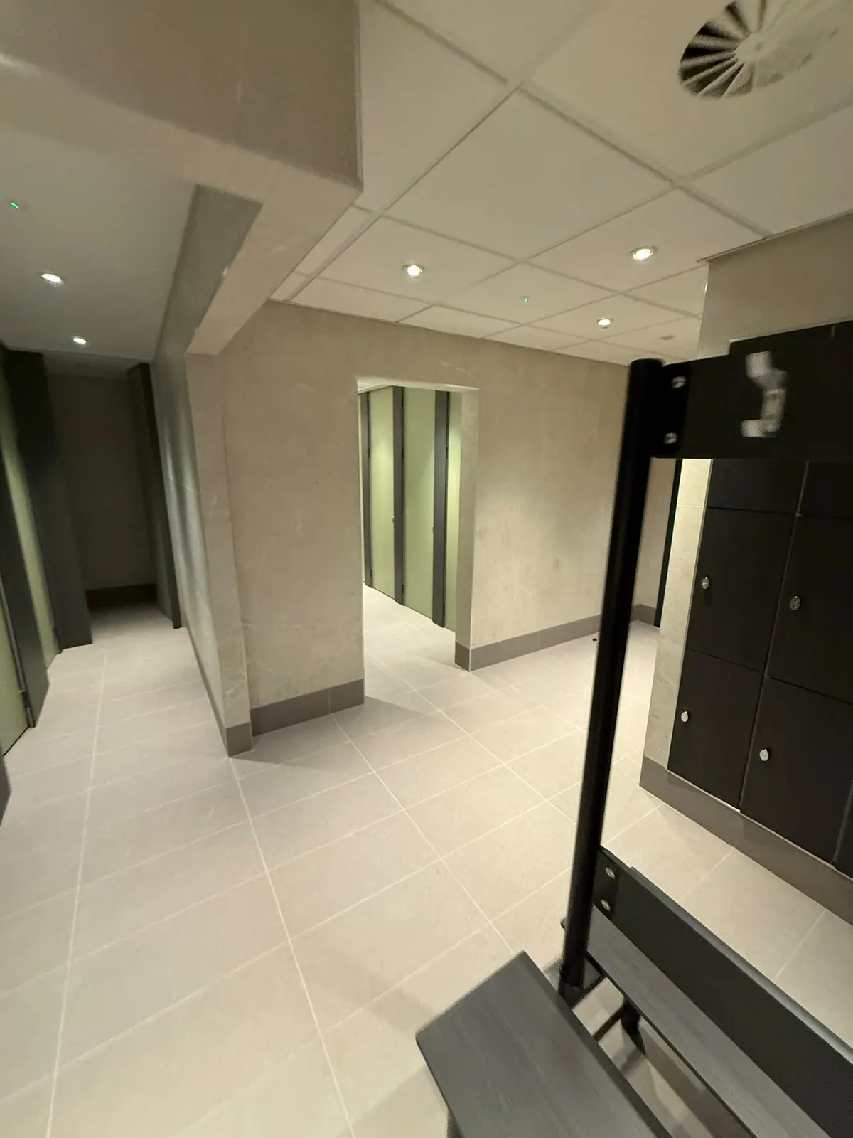 Lockers and bench seating in the changing room, with EXT Core Grey 600 × 300 floor tiles running through to the cubicles