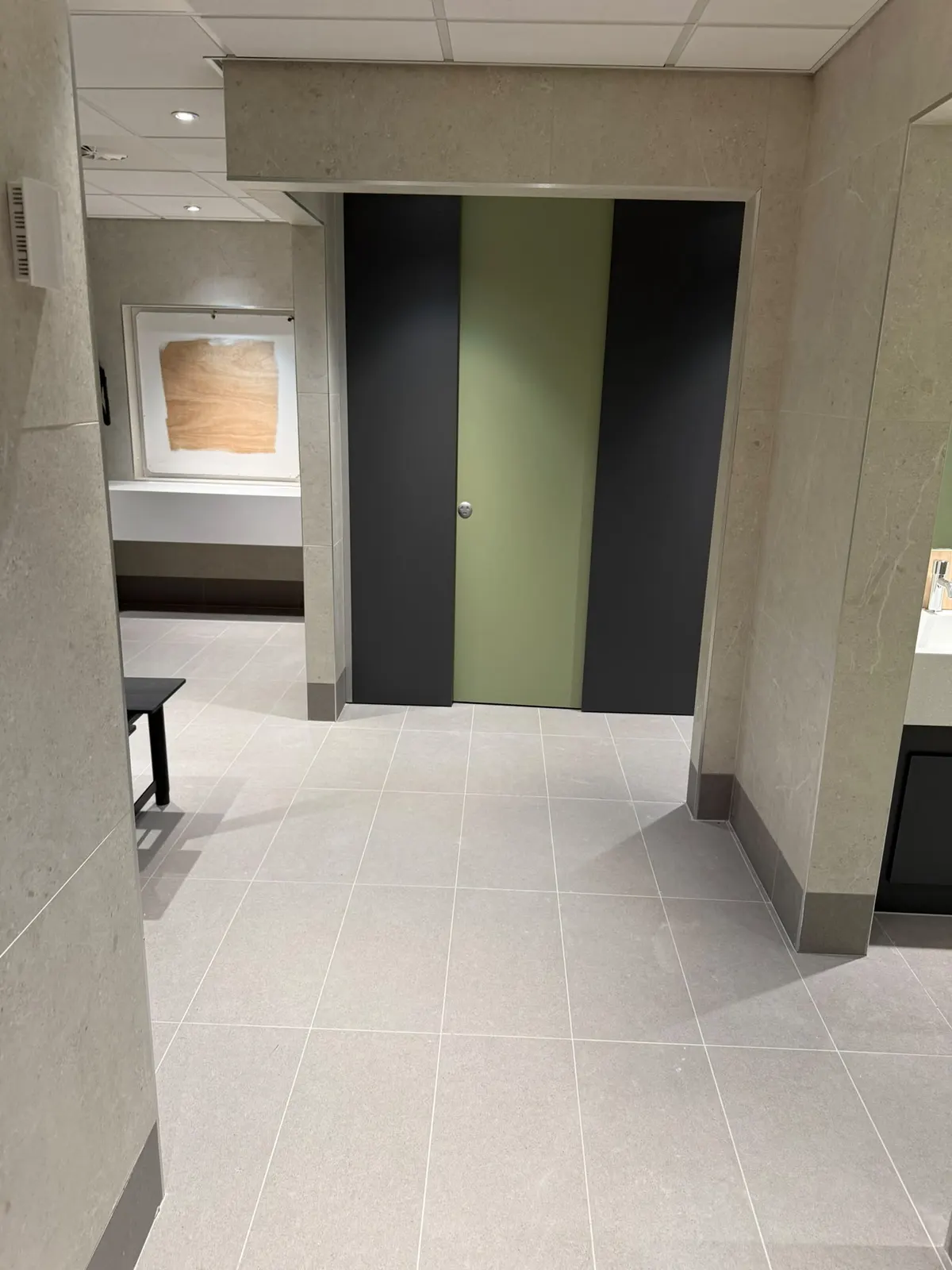 Changing room doorway and cubicle doors framed by Unika Light 600 × 600 wall tiles