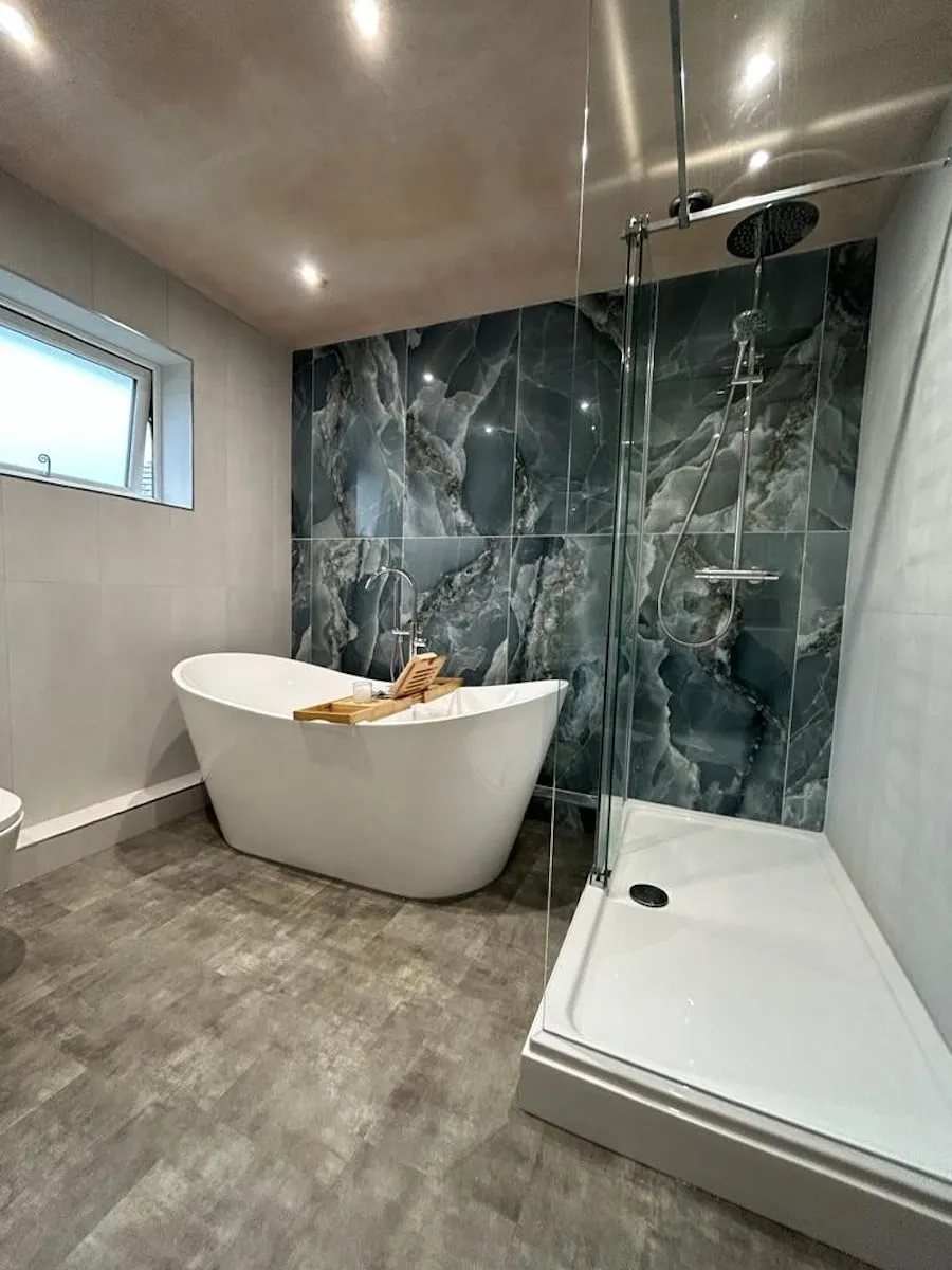 Freestanding bath and walk-in shower against a green onyx-effect feature wall, Euxton