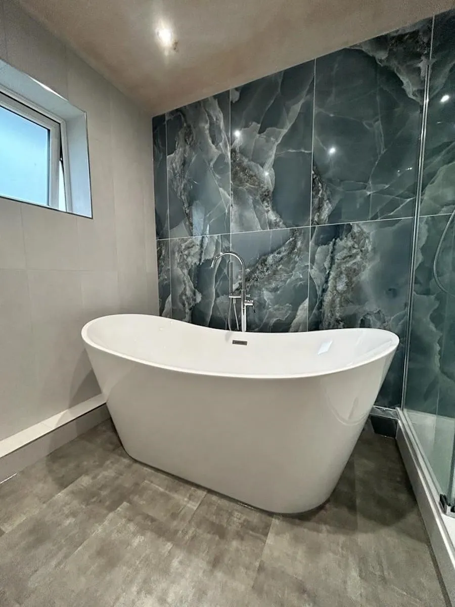 Large-format onyx-effect tiles behind the freestanding bath