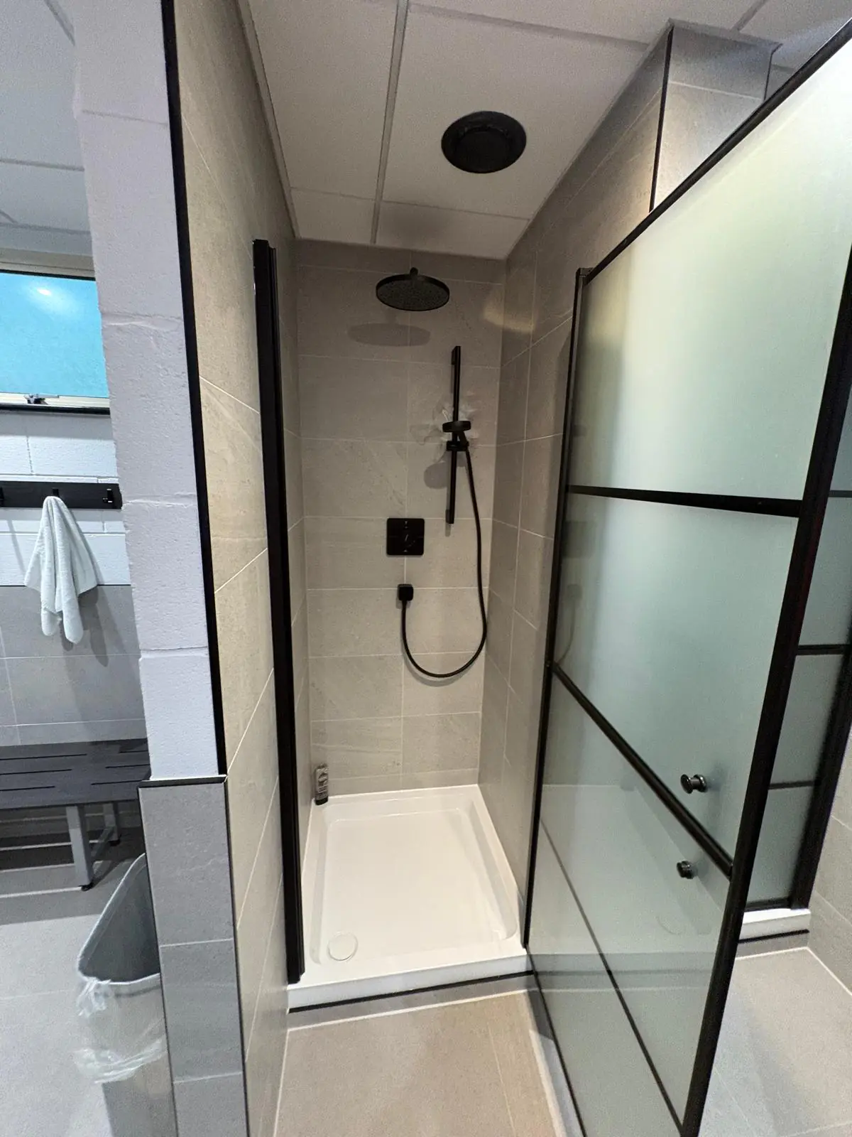 Inside a tanked shower cubicle, tiled floor to ceiling in Soft Spartia Perla 300 × 600