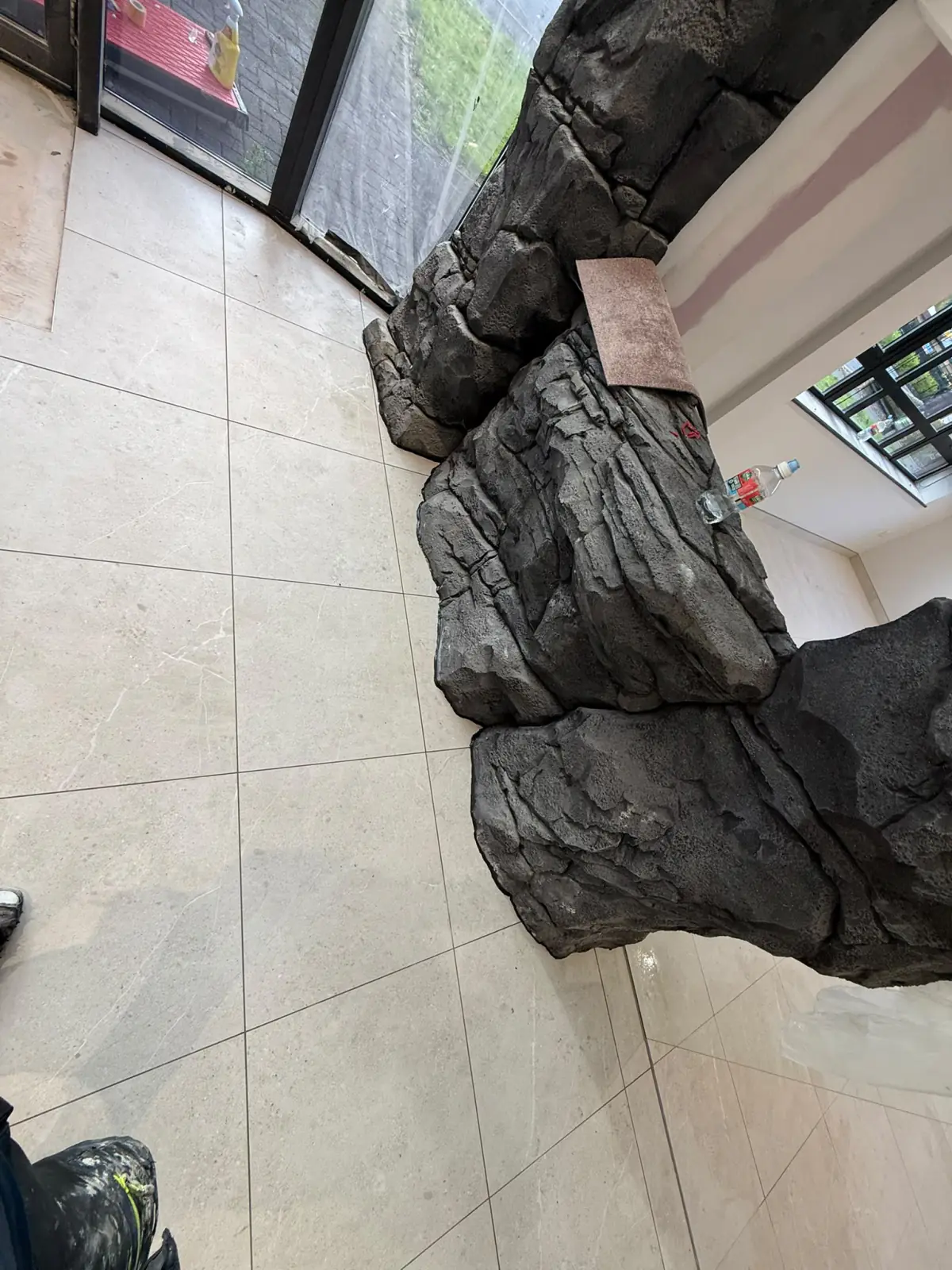 Floor tiles scribed around the base of the rock cladding