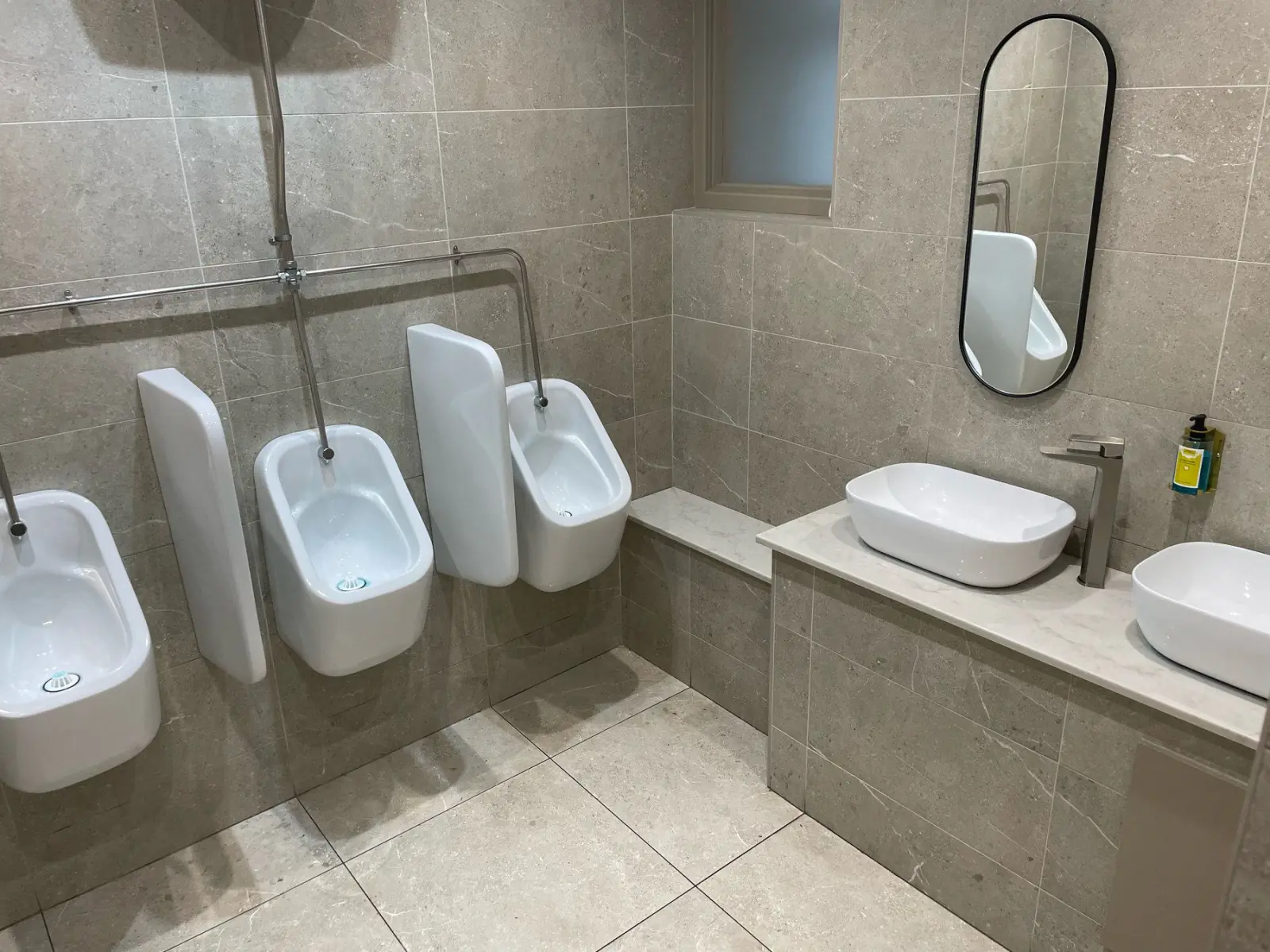 Gents urinals and vanity, walls in Unika Bone 600 × 300 with Asteroid Grey trims