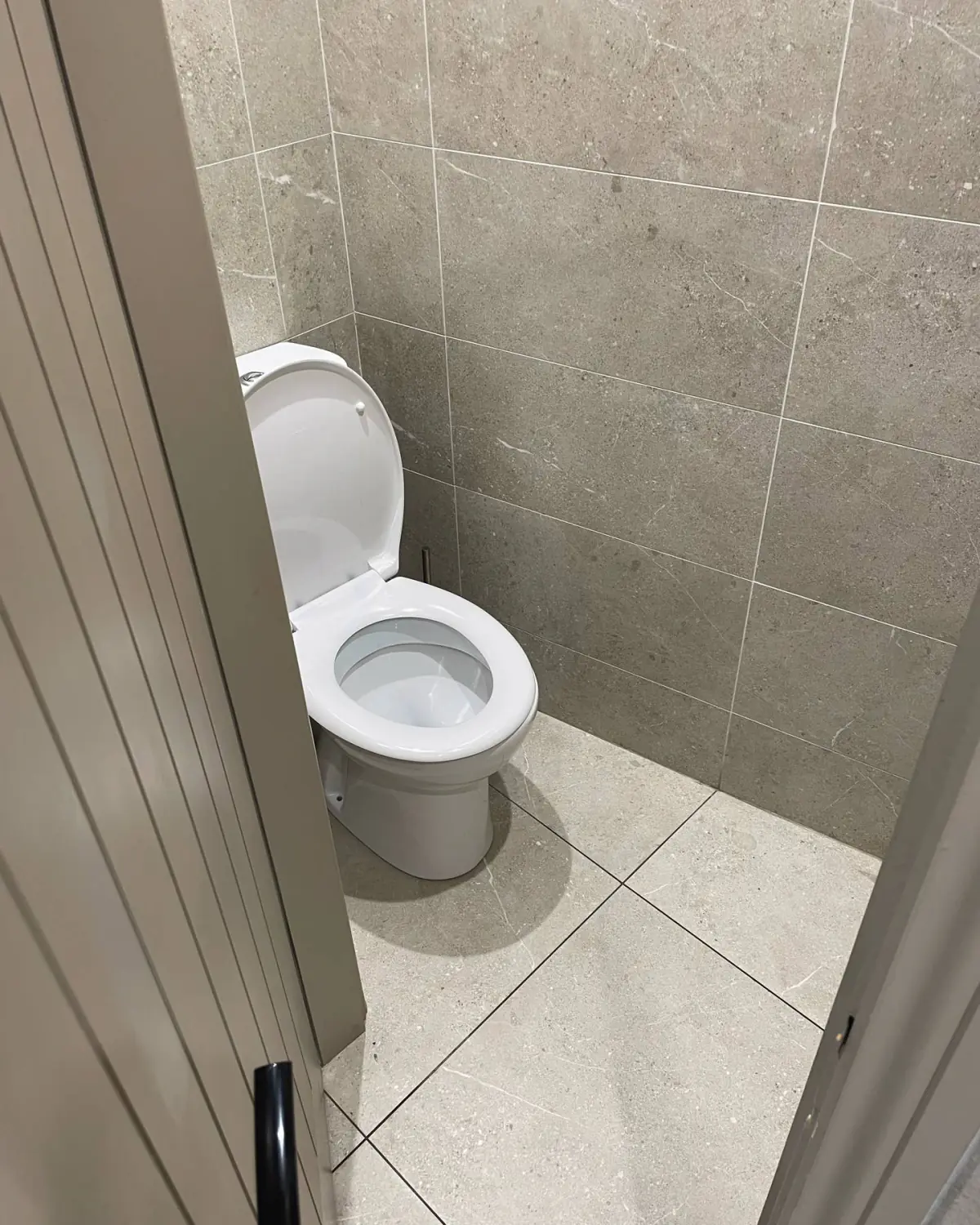 Gents WC cubicle in Unika Bone, 600 × 300 on the walls and 600 × 600 on the floor