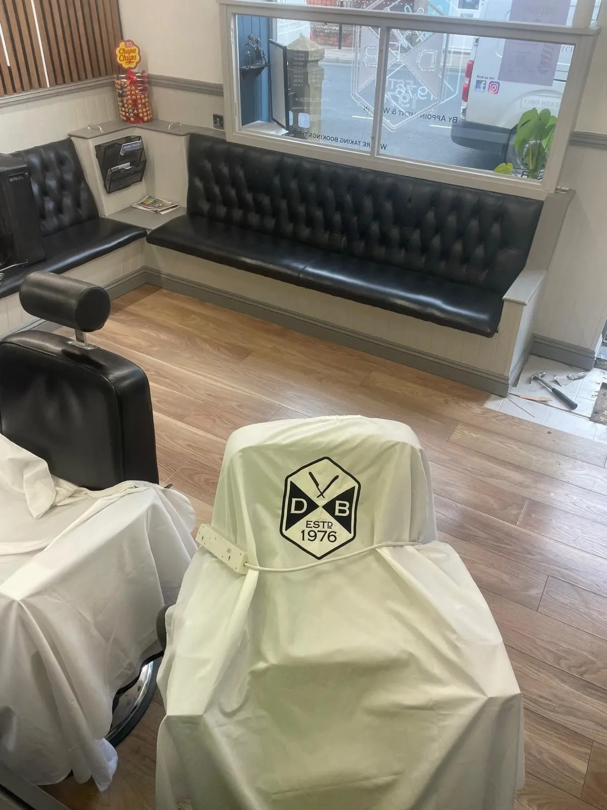 Dalbys Barbers with wood-effect floor tiles and black leather seating