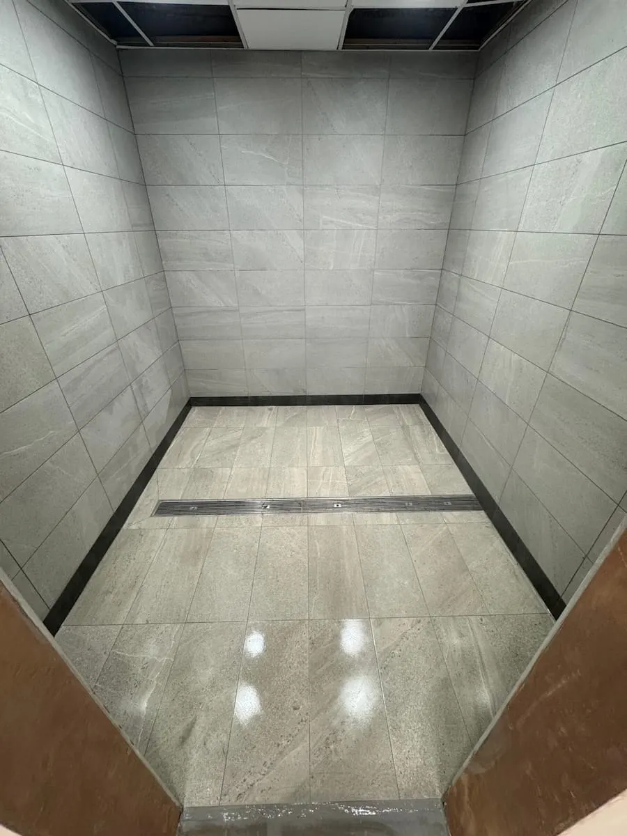 Grey porcelain floor and walls with a dark inlay strip in a leisure centre changing area