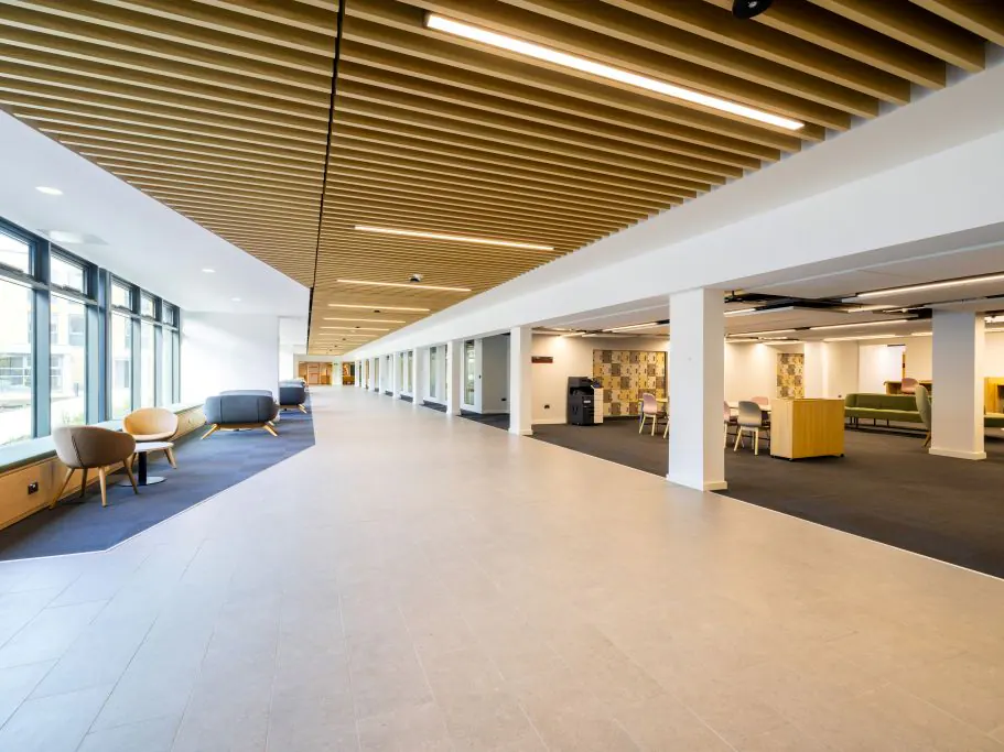 Light grey large-format porcelain floor running the length of a concourse at Lancaster University, between carpeted study areas