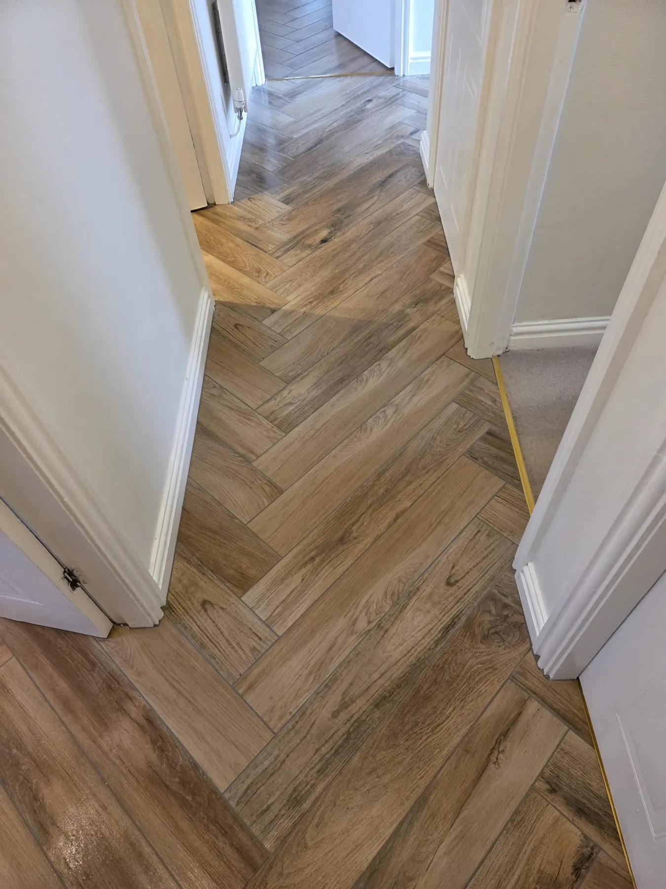 Wood-effect herringbone tiles along a narrow hallway