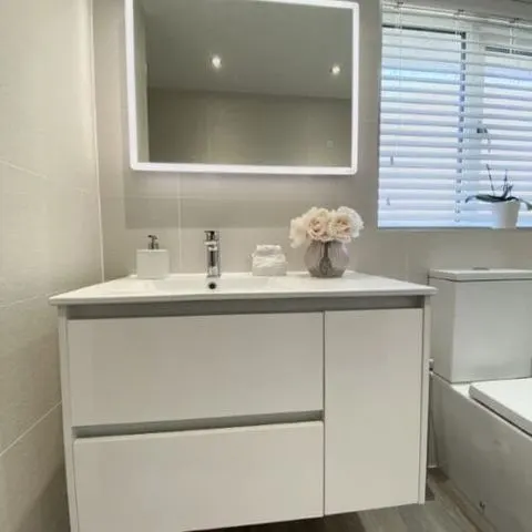 Finished bathroom with a white vanity and illuminated mirror