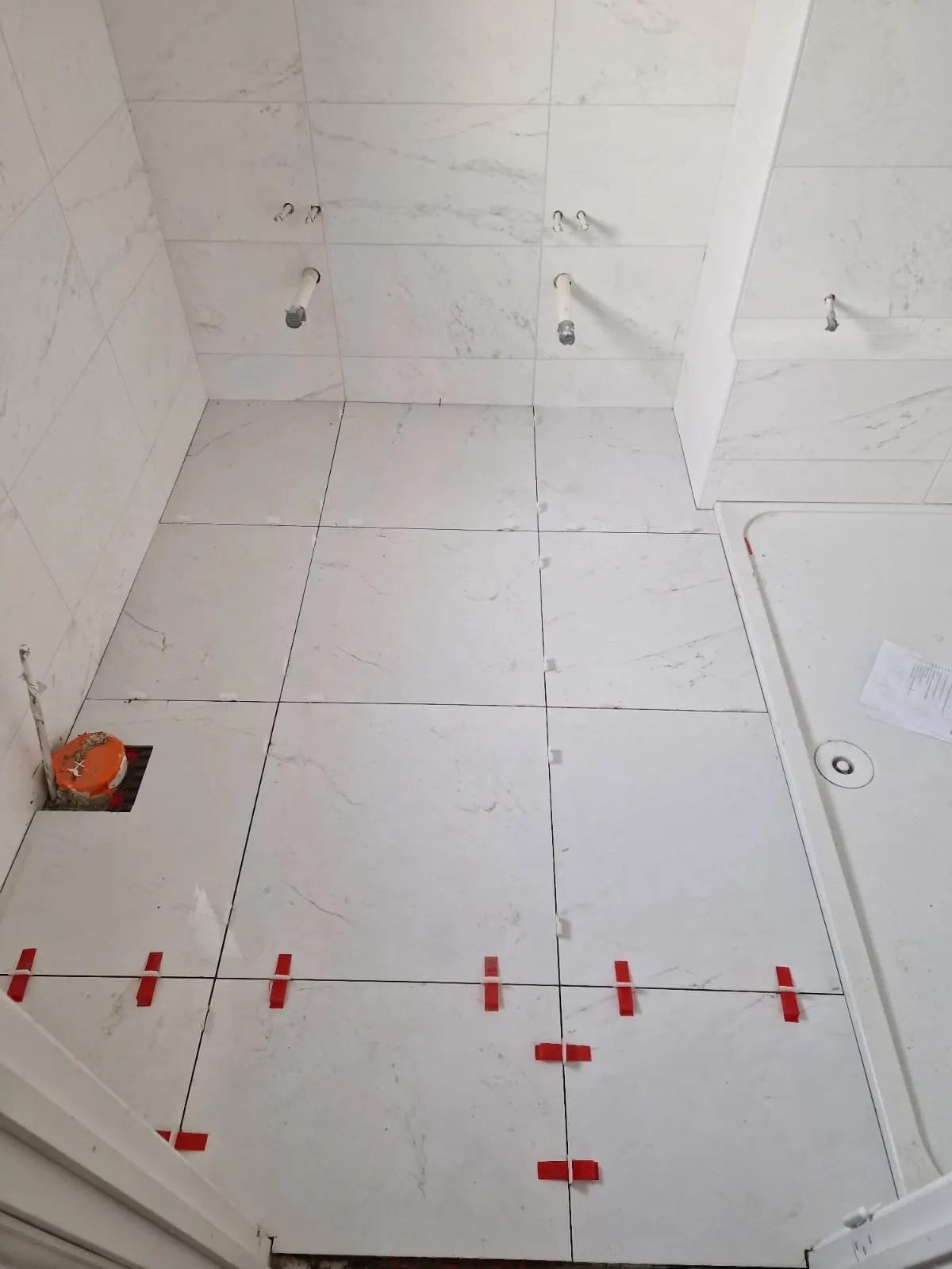Large-format floor tiles being laid with levelling clips at Sycamore Manor