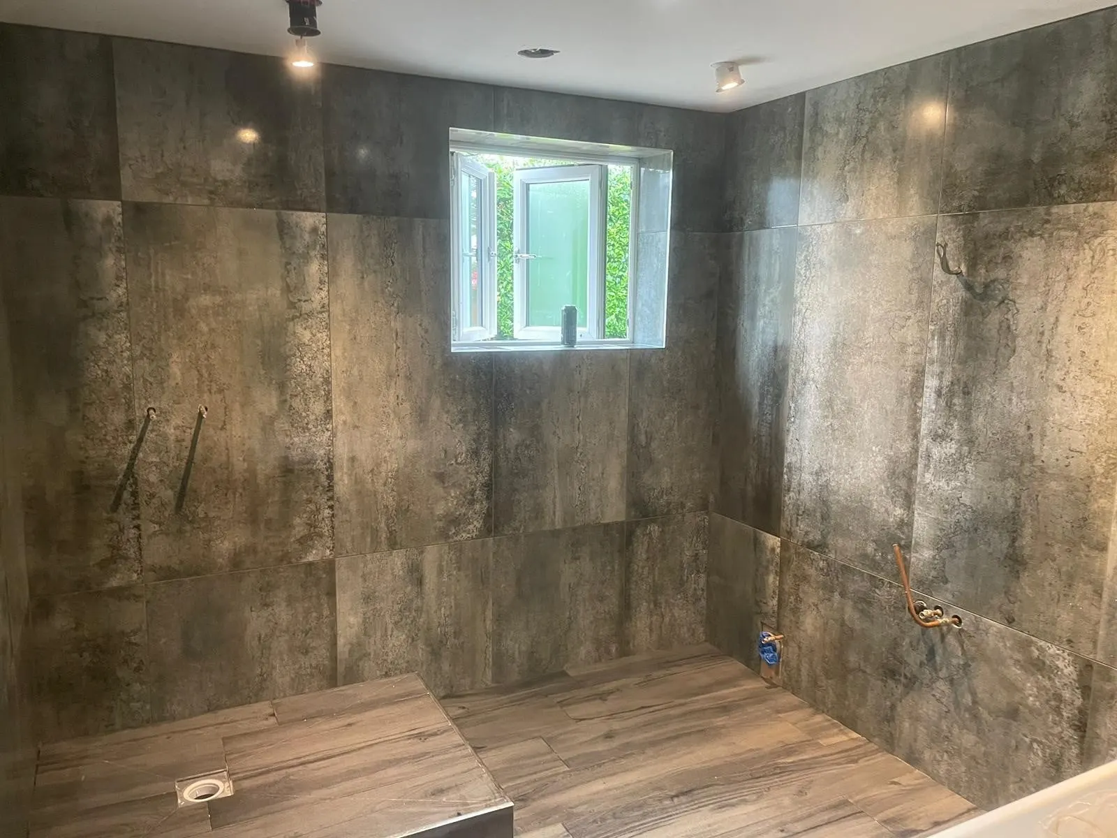 Dark stone-effect wall tiles in a wet room before fit-out