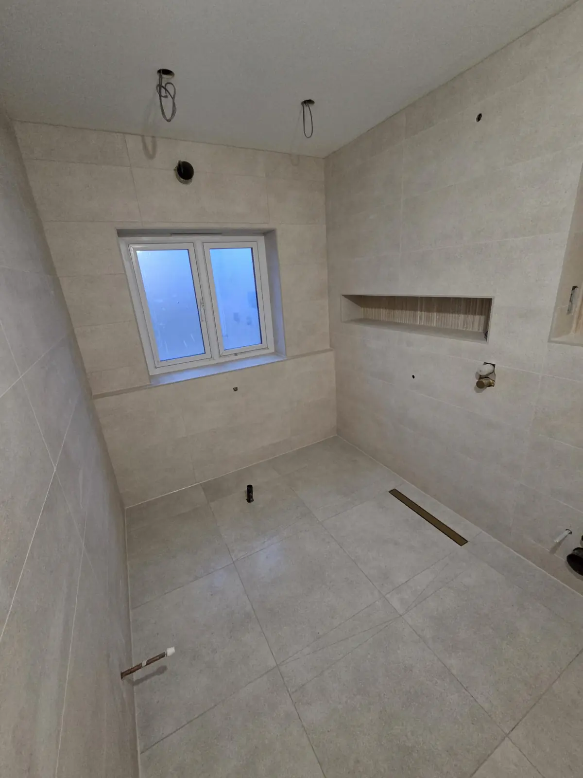 Level wet room floor in large-format stone-effect porcelain with a linear drain, before fit-out