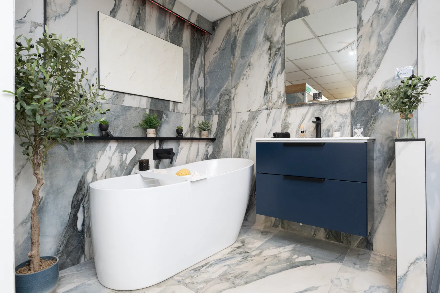Blue-veined marble-effect walls and floor around a freestanding bath in a showroom setting