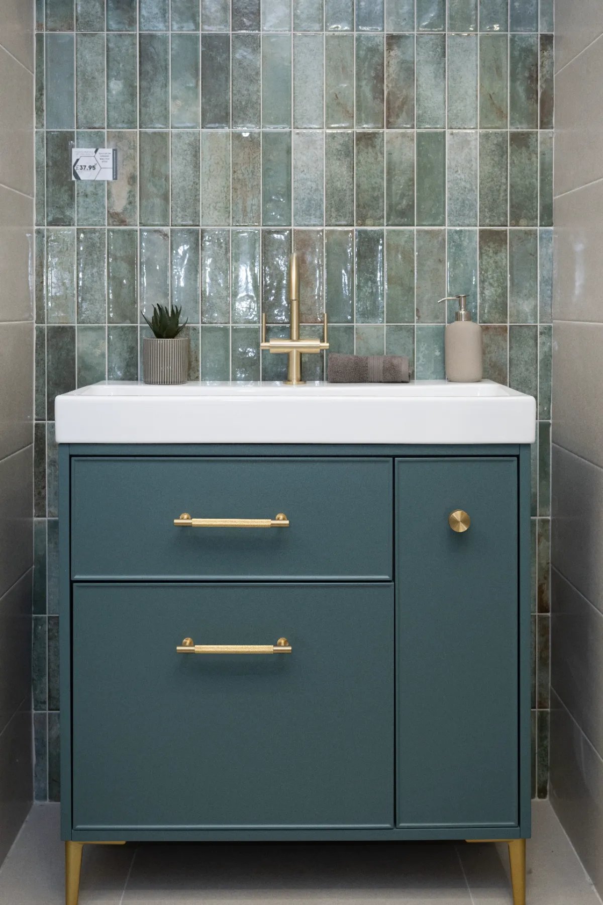 Green gloss vertical tiles behind a teal vanity with brass fittings