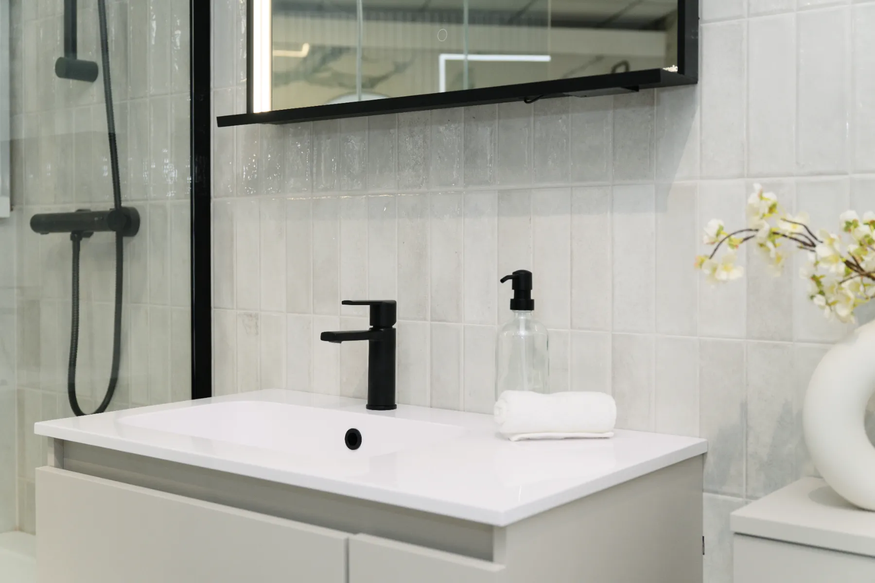 Pale grey vertical tiles above a vanity with a black tap