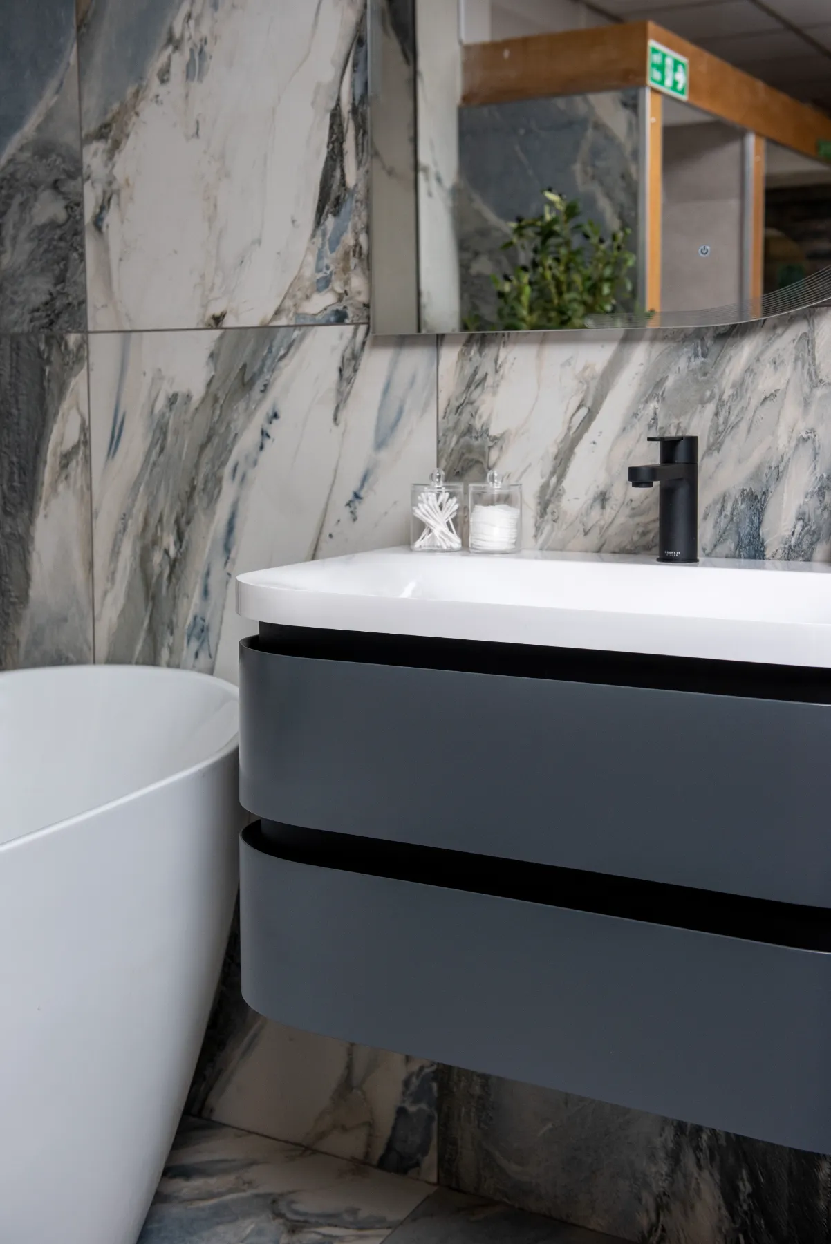 Marble-effect wall tiles behind a curved grey vanity